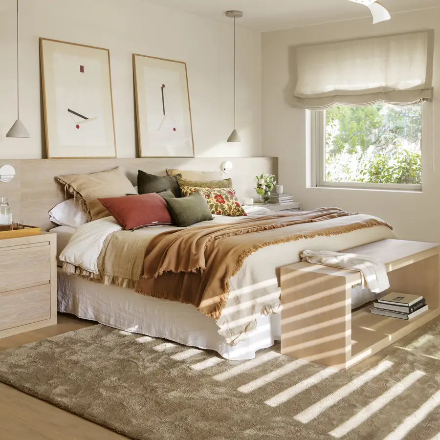 dormitorio principal con cabecero de obra, cuadros, ropa de cama beige, marrón, flores, morado y verde, estor y ventilador de techo y alfombra